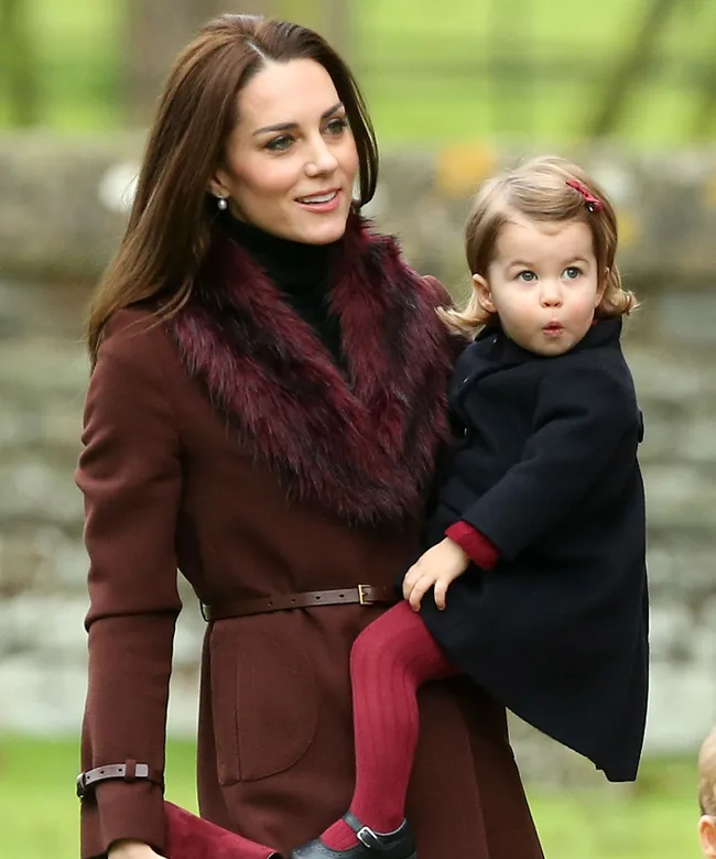 Mother holding young child outdoors, both dressed warmly.