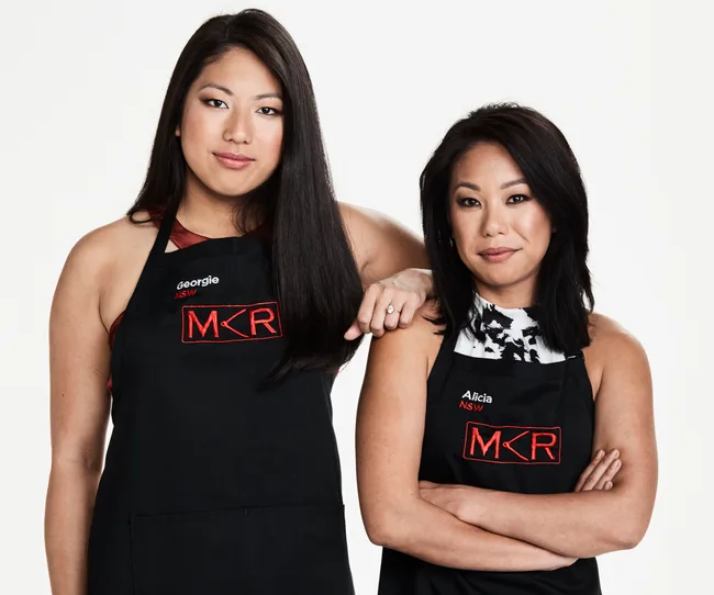 Two women wearing "MKR" aprons, one with "Georgie" and the other with "Alicia" named on them, posing together.