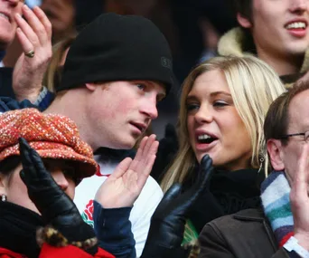 A man and woman talking in a crowd at a sports event, both are dressed warmly.