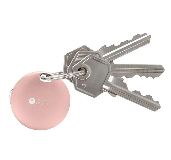 A set of silver keys with a round, pink Orbit key tracker attached.