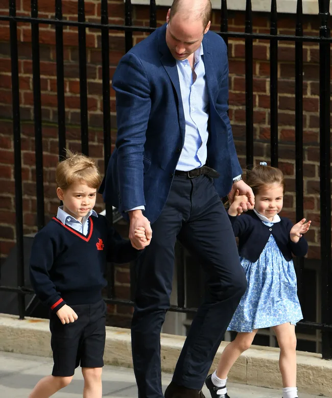 Father with two young children, holding hands, walking outside a hospital.