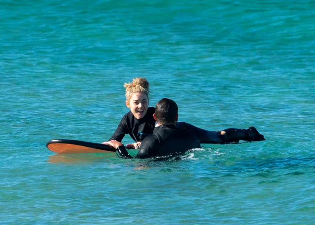 Two people in wetsuits enjoy surfing together in the ocean.