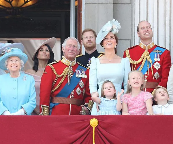 A group of well-dressed people, possibly a family, standing together on a balcony, looking up at the sky.