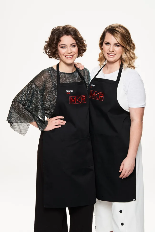 Two women wearing black aprons with "MKR" logos, smiling at the camera.