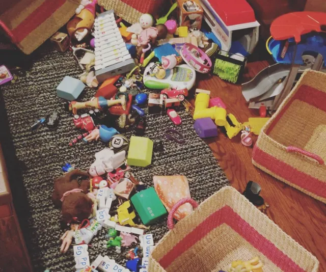 Scattered children's toys on a carpet with empty woven storage baskets nearby.