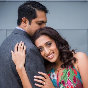 Couple embracing, woman smiling at camera, man resting his head on hers.