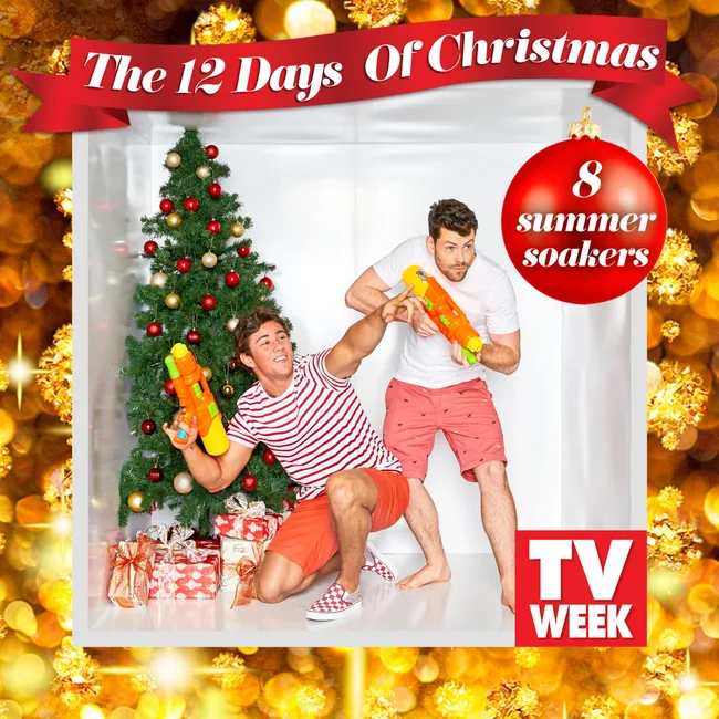 Two men in festive outfits holding water guns by a Christmas tree with gifts, text reads "The 12 Days of Christmas."