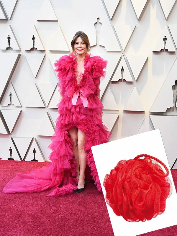 A person in a bold, pink ruffled dress on a red carpet, with a loofah comparison in the corner.