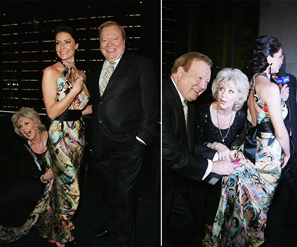 Three people in formal attire pose playfully at an event. A woman holds another's dress train, and a man smiles beside them.
