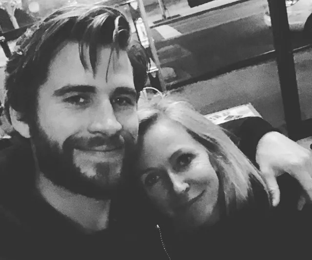 Man and woman smiling arm-in-arm in a black-and-white photo outside.