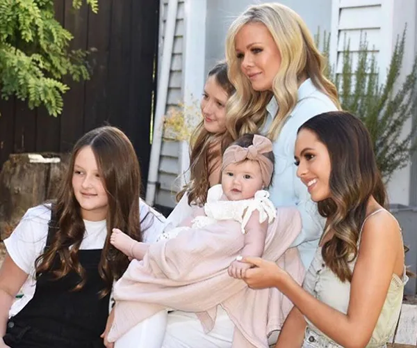 Four women and a baby pose together outdoors, smiling.