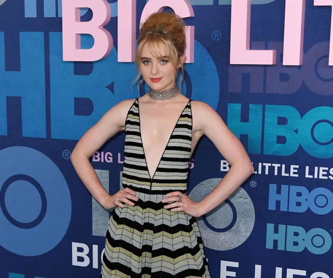 Person in a striped dress at the "Big Little Lies" event, standing in front of an HBO backdrop.