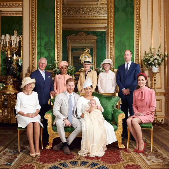 Royal family members posing during a christening ceremony in an ornate room with green and gold accents.