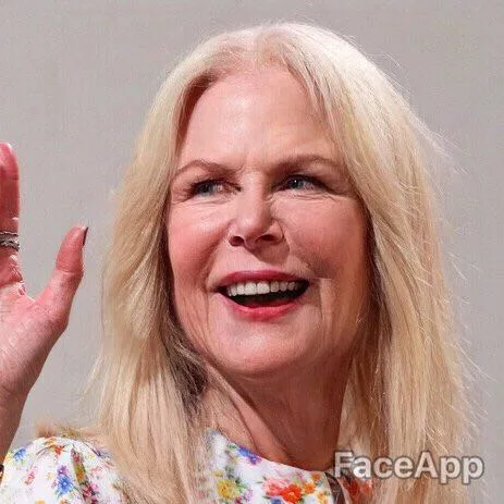 Old woman with long blonde hair smiling and waving, wearing a floral top. FaceApp watermark visible in the bottom corner.