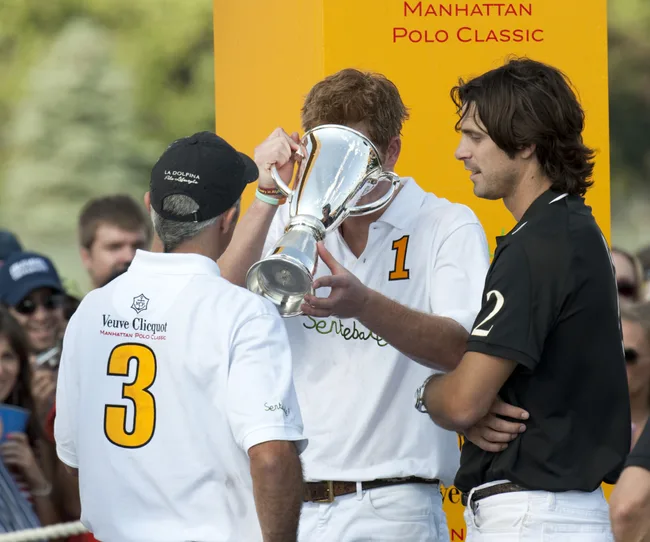 "Polo players congratulating each other; one holding a trophy at the Manhattan Polo Classic."
