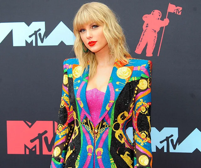 Singer in colorful suit stands at MTV Video Music Awards backdrop.