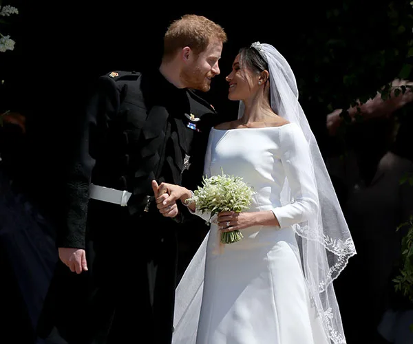 A bride and groom lovingly look at each other on their wedding day, the groom in uniform and the bride in a white dress.