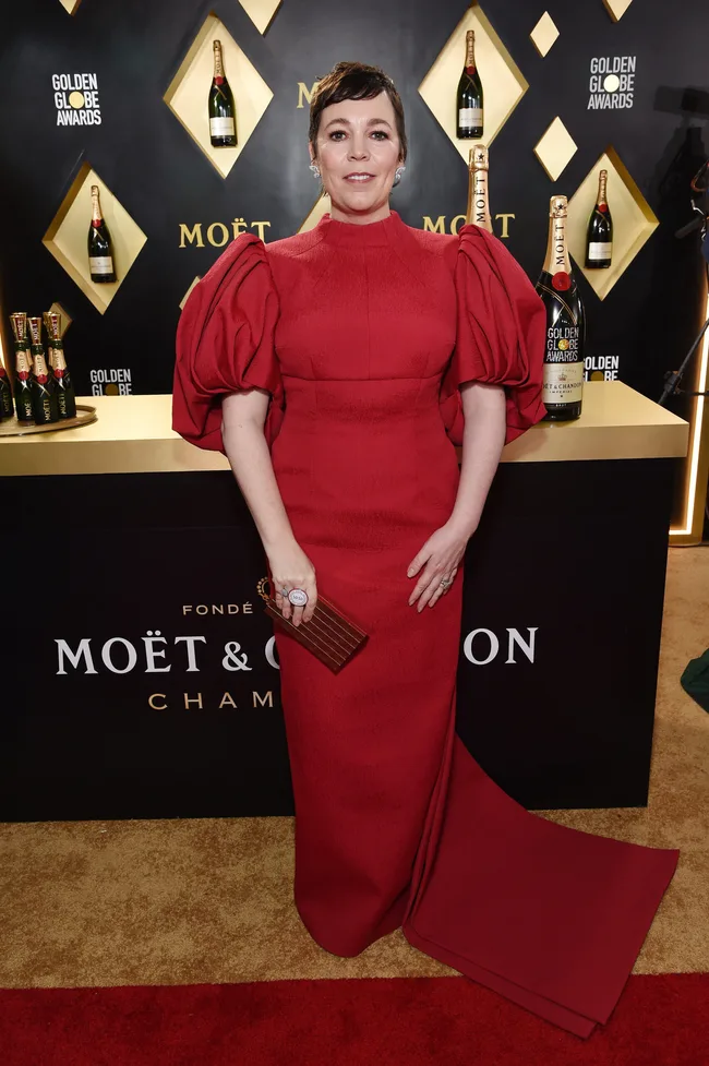 Person in a red gown at the Golden Globe Awards with Moët & Chandon bottles in the background.