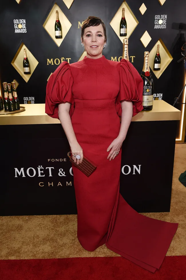 Person in a red gown at the Golden Globe Awards with Moët & Chandon bottles in the background.