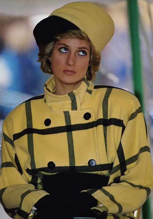Person wearing a yellow plaid coat and matching hat looks upward thoughtfully.
