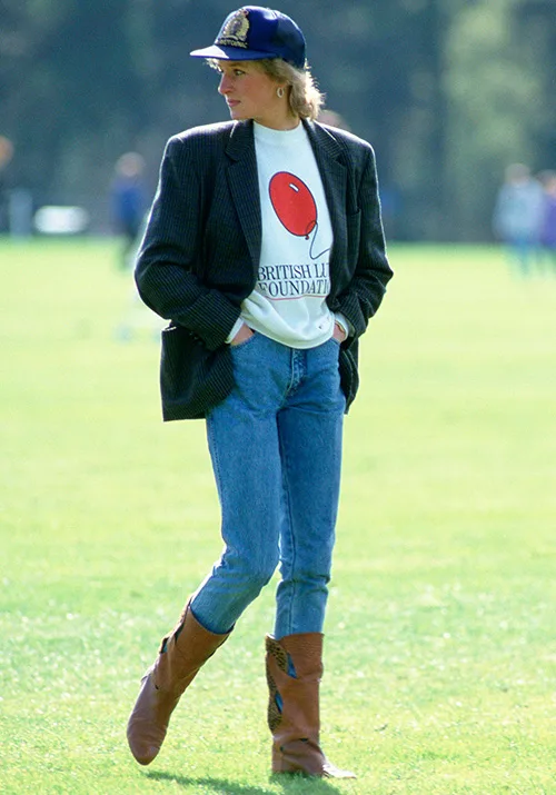 Alt text: Person in a cap, blazer, and jeans walks on grass, wearing a "British Lung Foundation" shirt and brown boots.