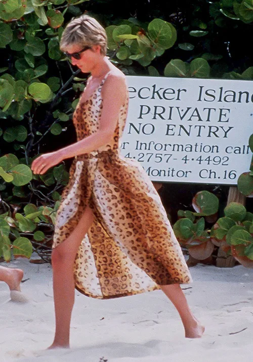 Person in leopard-print dress walking on beach near "Private No Entry" sign.