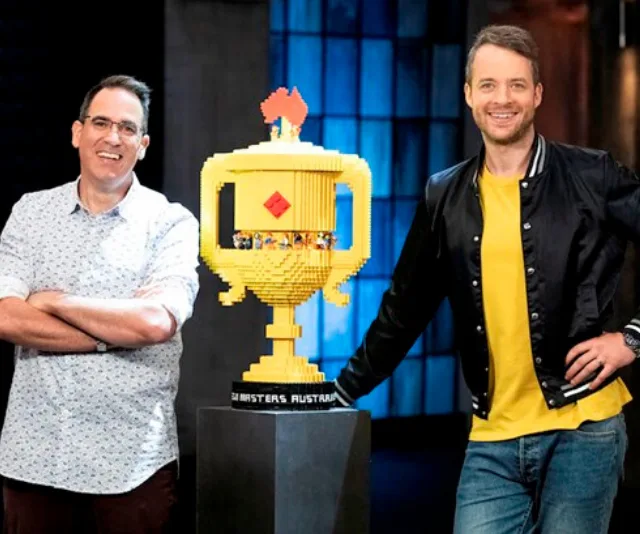 Two men standing beside a large LEGO trophy on "LEGO Masters Australia."