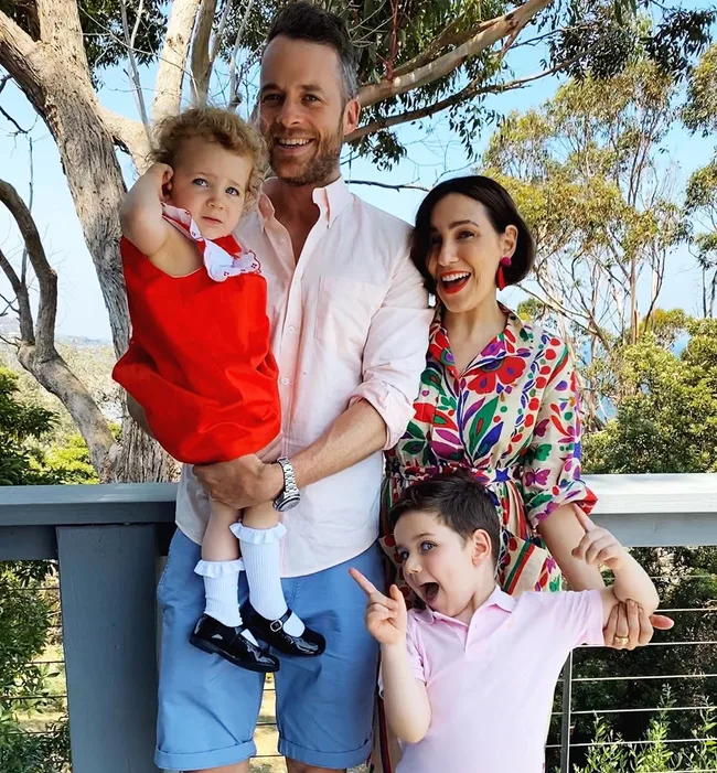 A family posing happily on a porch with trees in the background.