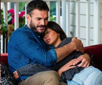 Couple embracing affectionately on a cozy porch setting, conveying warmth and intimacy.