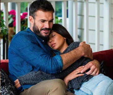 Couple embracing affectionately on a cozy porch setting, conveying warmth and intimacy.
