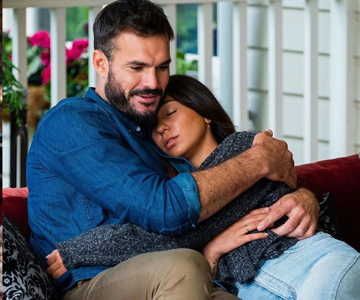 Couple embracing affectionately on a cozy porch setting, conveying warmth and intimacy.