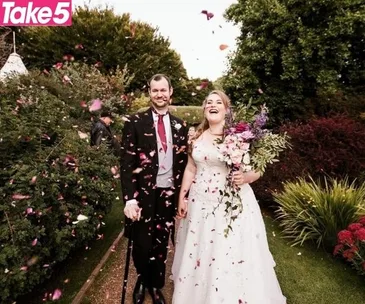 Bride and groom smiling as guests throw confetti in a garden wedding setting.