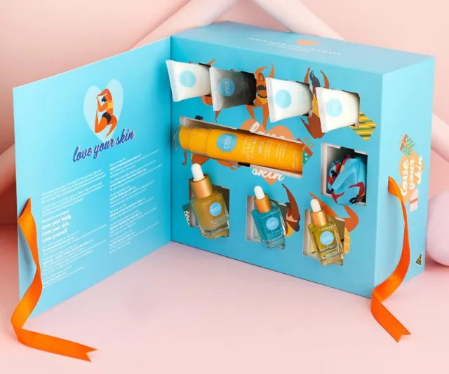 Open skincare gift set with various bottles and tubes, featuring colorful packaging and an orange ribbon.
