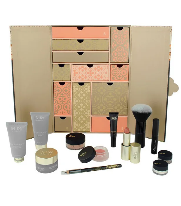 "Cosmetic advent calendar with skincare and makeup products, including creams, lipstick, and brushes, on display."