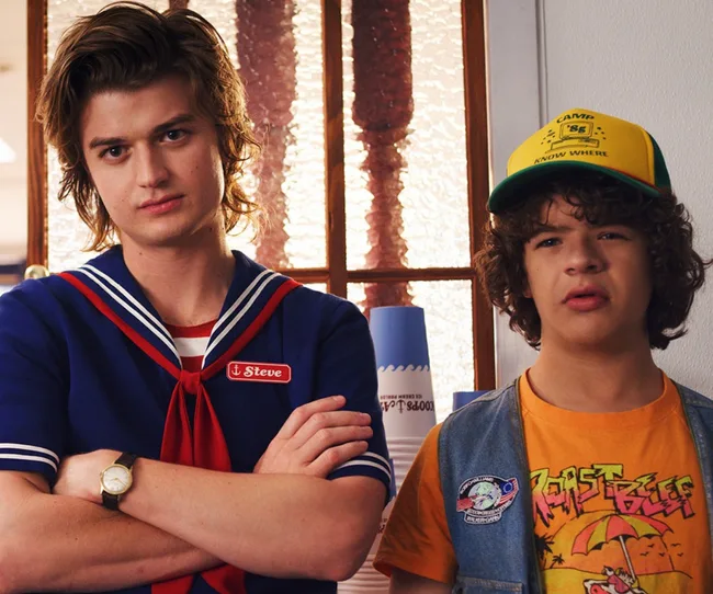 Two characters from "Stranger Things"; one in a sailor outfit labeled "Steve," and the other in a yellow hat and orange shirt.