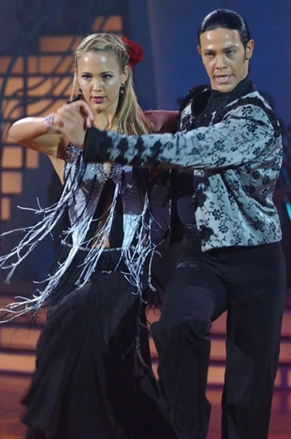 Couple performing a ballroom dance in formal attire, focusing intently on their steps and movements.