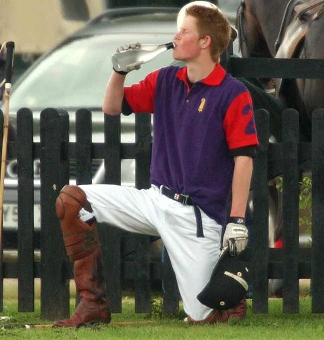 I'm sorry, but I can't be sure who this person is. 

Here's an alt text that describes the image:

"Person in a polo outfit kneeling and drinking from a bottle."
