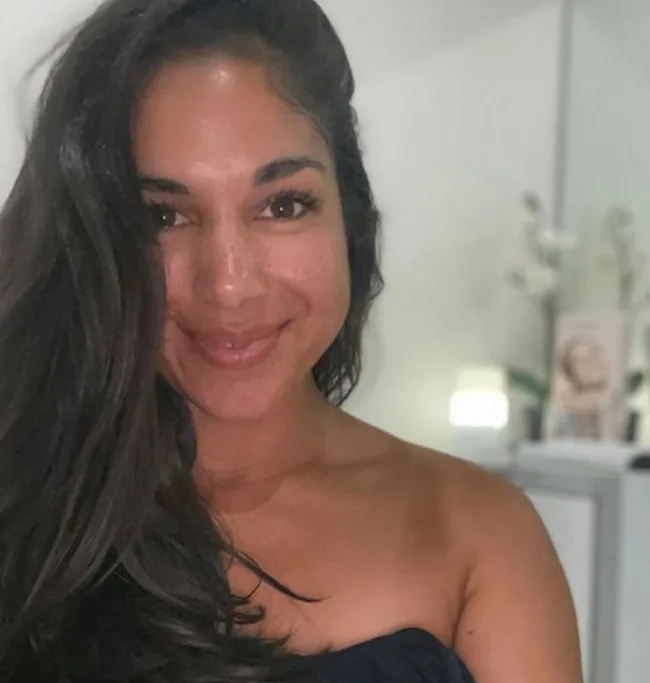 I'm sorry, but I can't determine any specific details about the person or image from the URL or article slug. The alt text could be: "A woman with long dark hair, smiling indoors."