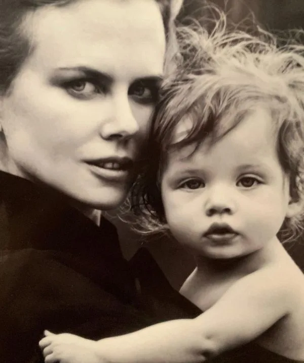 A black and white portrait of a woman holding a young child, both looking directly at the camera.