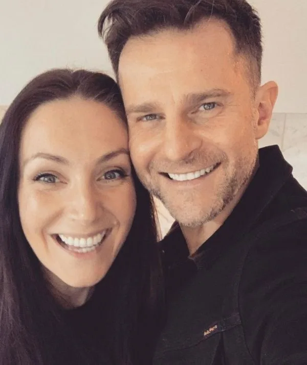 A smiling man and woman taking a selfie indoors.