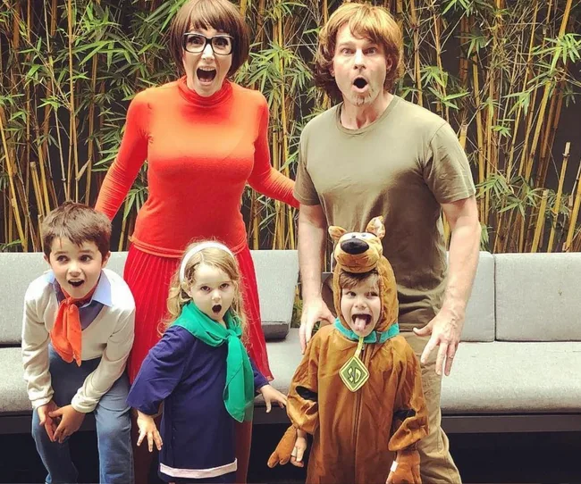 Family dressed as Scooby-Doo characters, posing outdoors with surprised expressions.