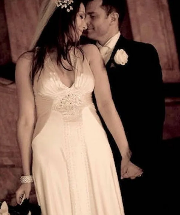 Bride and groom hold hands, smiling intimately in wedding attire.