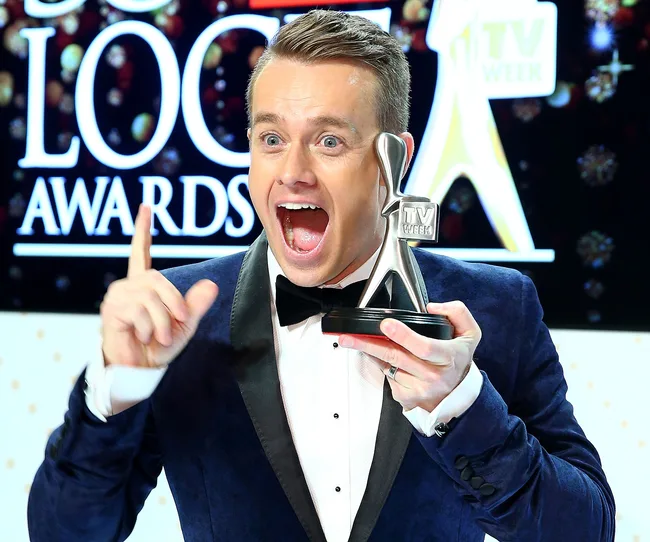 Man in a tuxedo excitedly holding a TV Week Logie Award on stage.