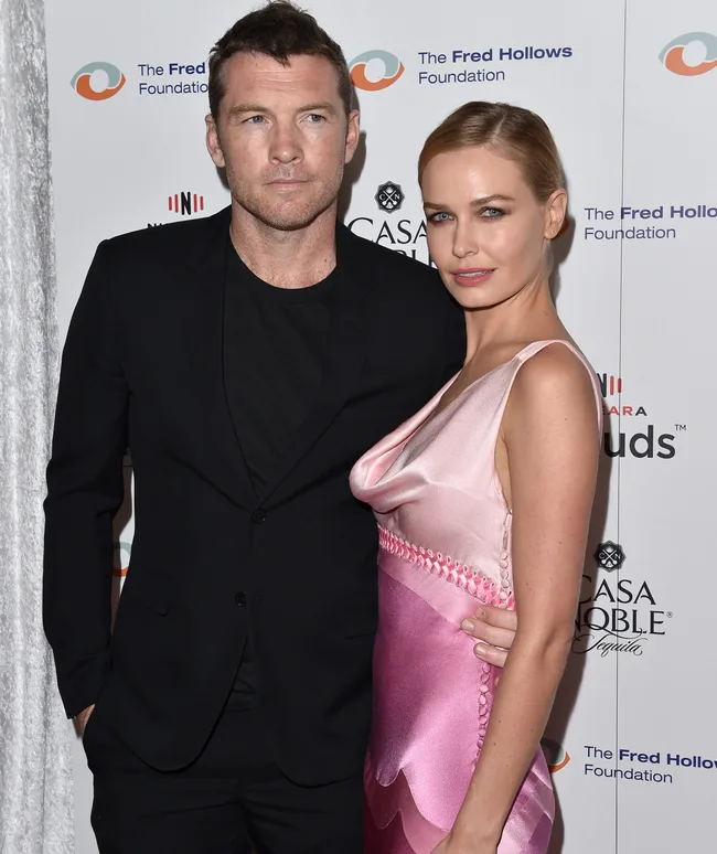 A man and woman posing together on the red carpet at The Fred Hollows Foundation event, wearing formal attire.