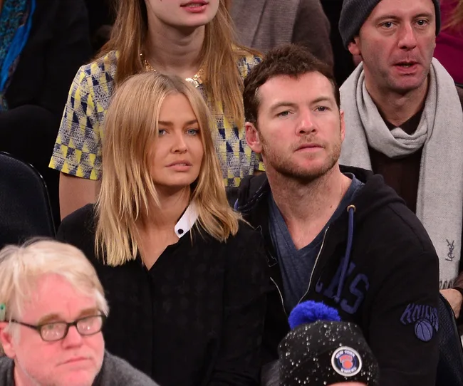 A couple sits at a sports event, surrounded by other spectators.