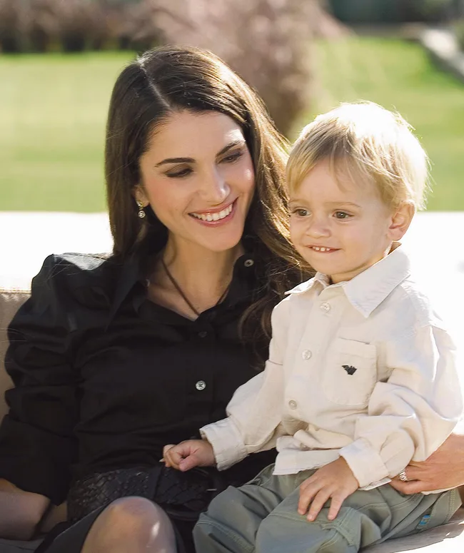 Woman smiling at a toddler on her lap in a garden setting.