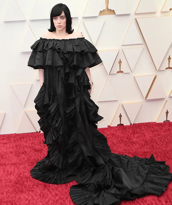"Person in black ruffled gown on red carpet at award event."