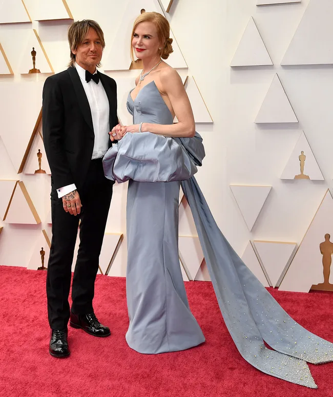 Nicole Kidman in a blue gown with a long train, posing on the Oscars 2022 red carpet.