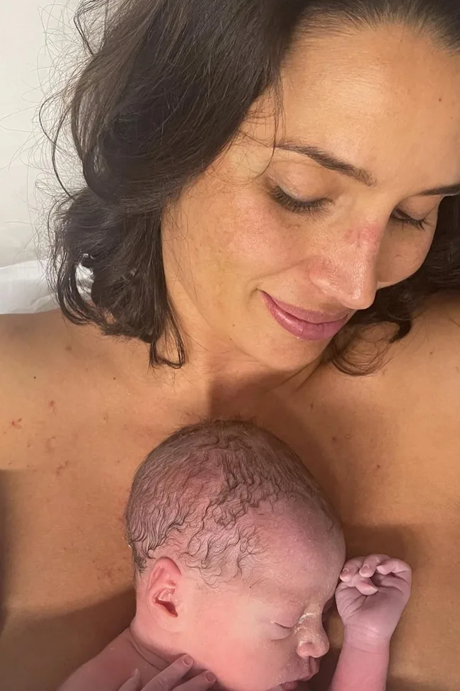 Mother cuddling a newborn, both with peaceful expressions.