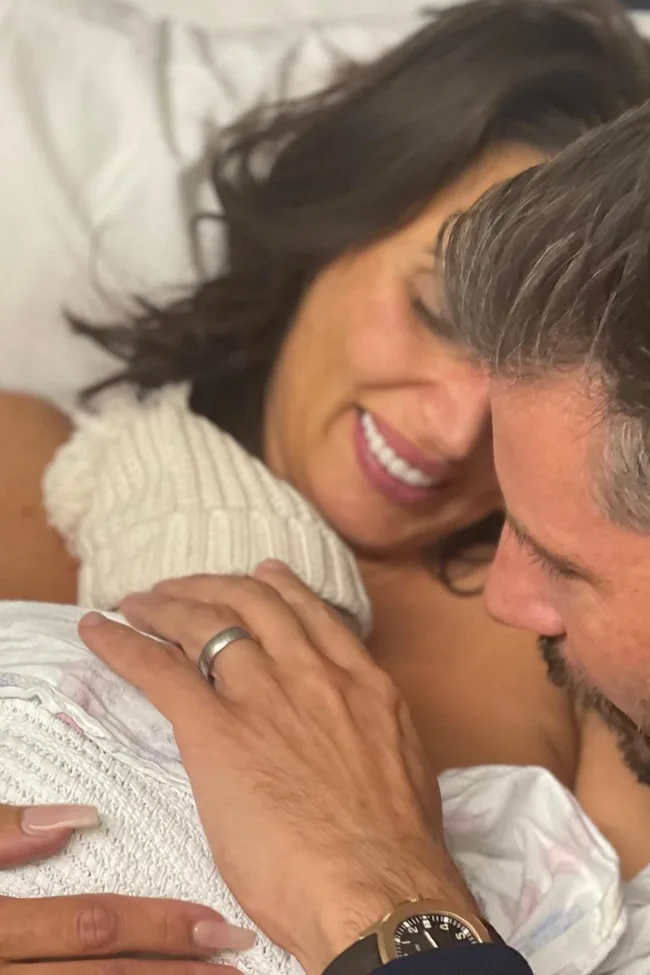 A couple lovingly gazes at their newborn wrapped in a blanket, capturing a tender family moment.